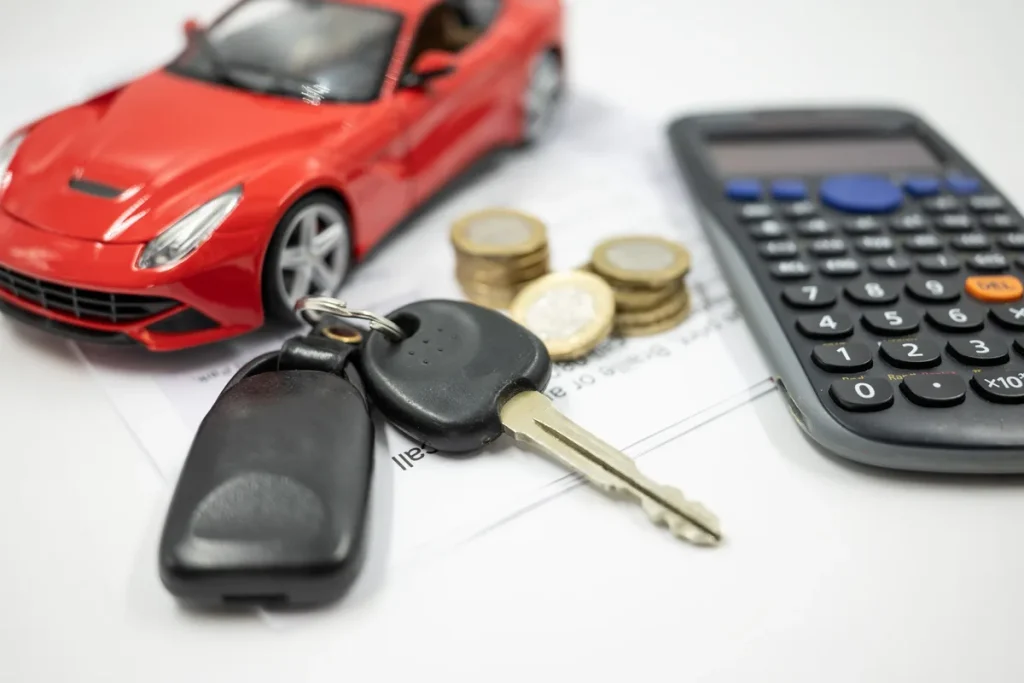 Speelgoedauto, autosleutels, munten en rekenmachine — symbool voor allrisk autoverzekering premie berekenen