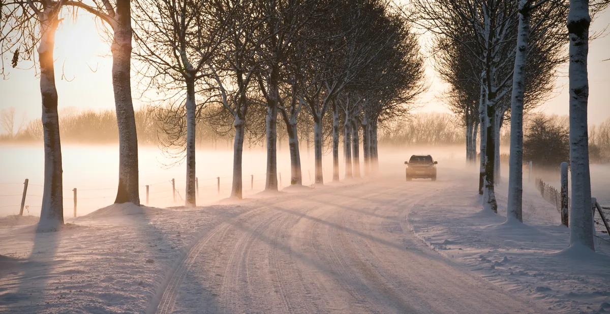 Auto rijdt op besneeuwde weg in Nederland in de winter - autoverzekering vergelijken en overstappen
