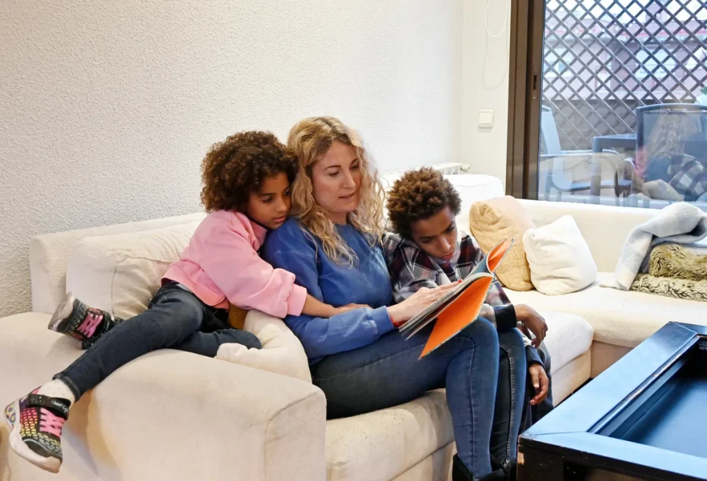 Moeder leest voor aan twee jonge kinderen op de bank, alleenstaande ouder met kinderen onder 18
