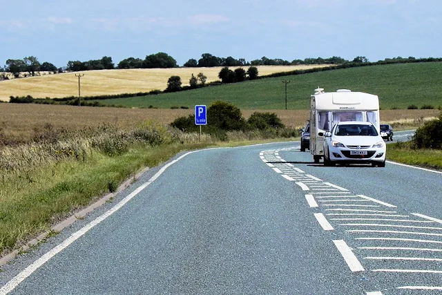 Auto trekt witte caravan op een landelijke weg — illustratie bij ANWB caravanverzekering 2026