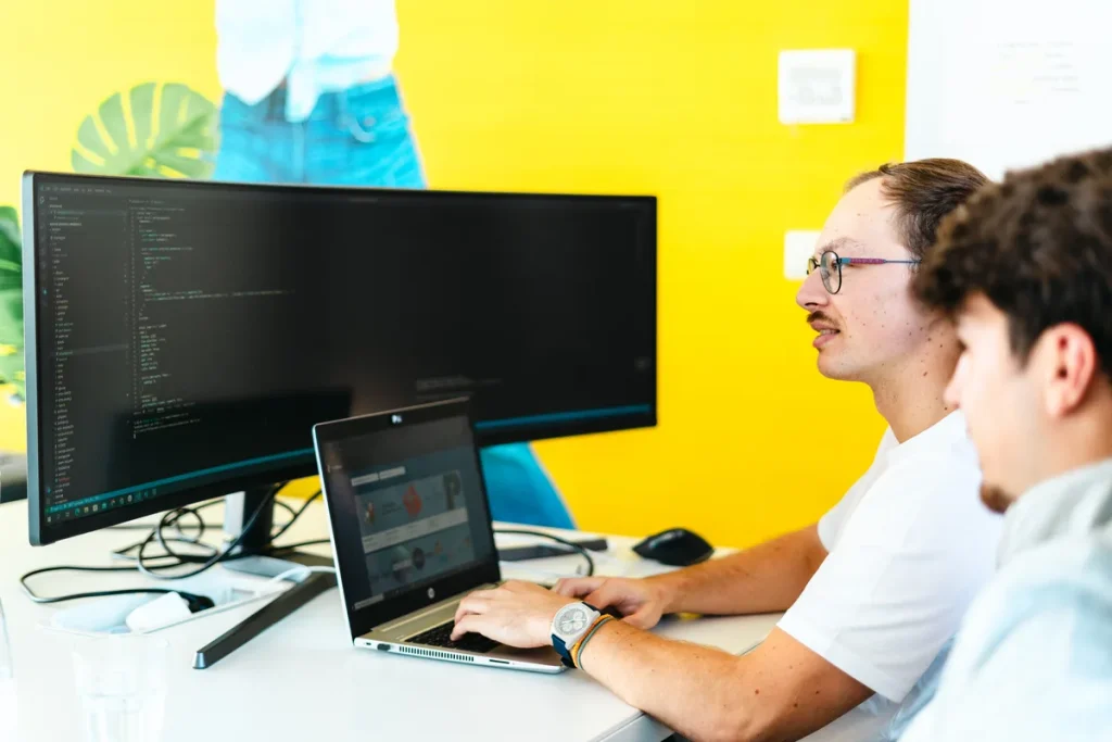 Twee ondernemers werken samen op laptop en monitor in modern kantoor — passend bij AOV zakelijk of privé afsluiten