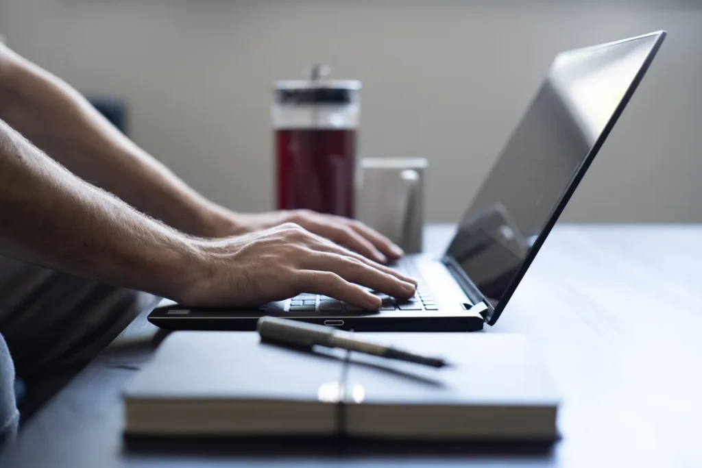 ZZP-er werkt thuis op laptop met notitieboekje — AOV beschermt inkomen bij arbeidsongeschiktheid