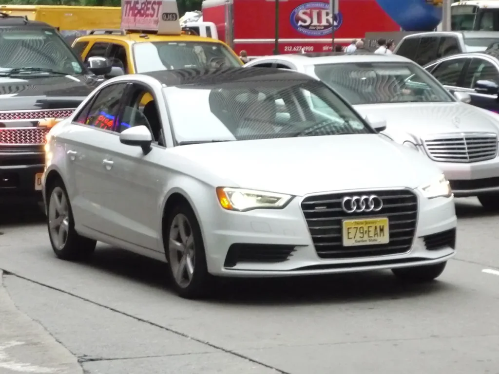 Witte Audi A3 sedan rijdend in stadsverkeer, autoverzekering kosten 2026