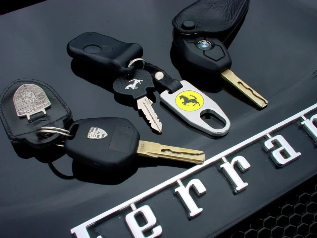 Autokleutels van Porsche, Ferrari en BMW op een motorkap — tijdelijke verzekering bij aankoop auto 2026