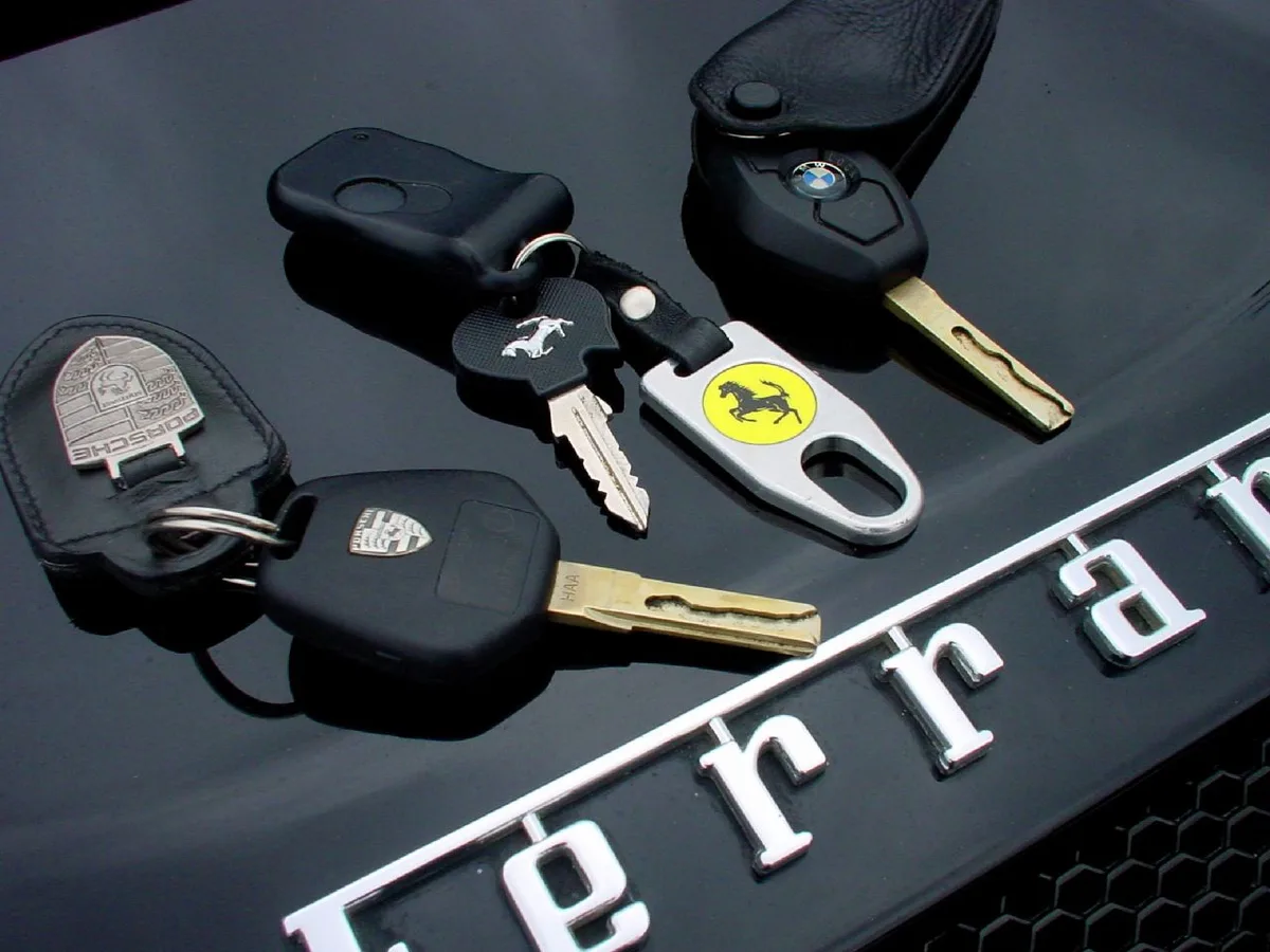 Autokleutels van Porsche, Ferrari en BMW op een motorkap — tijdelijke verzekering bij aankoop auto 2026