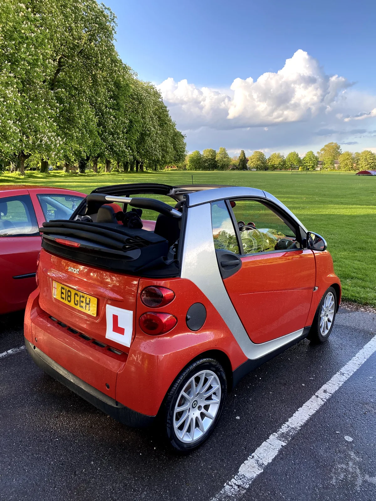 Compact leswagen met L-bordje geparkeerd in een park — auto op naam ouder voor kind verzekeren
