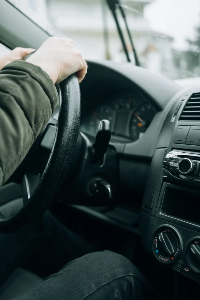 Jonge bestuurder gefocust op het stuur terwijl hij door besneeuwde straten rijdt — symbool voor rijervaring en autoverzekering opbouwen