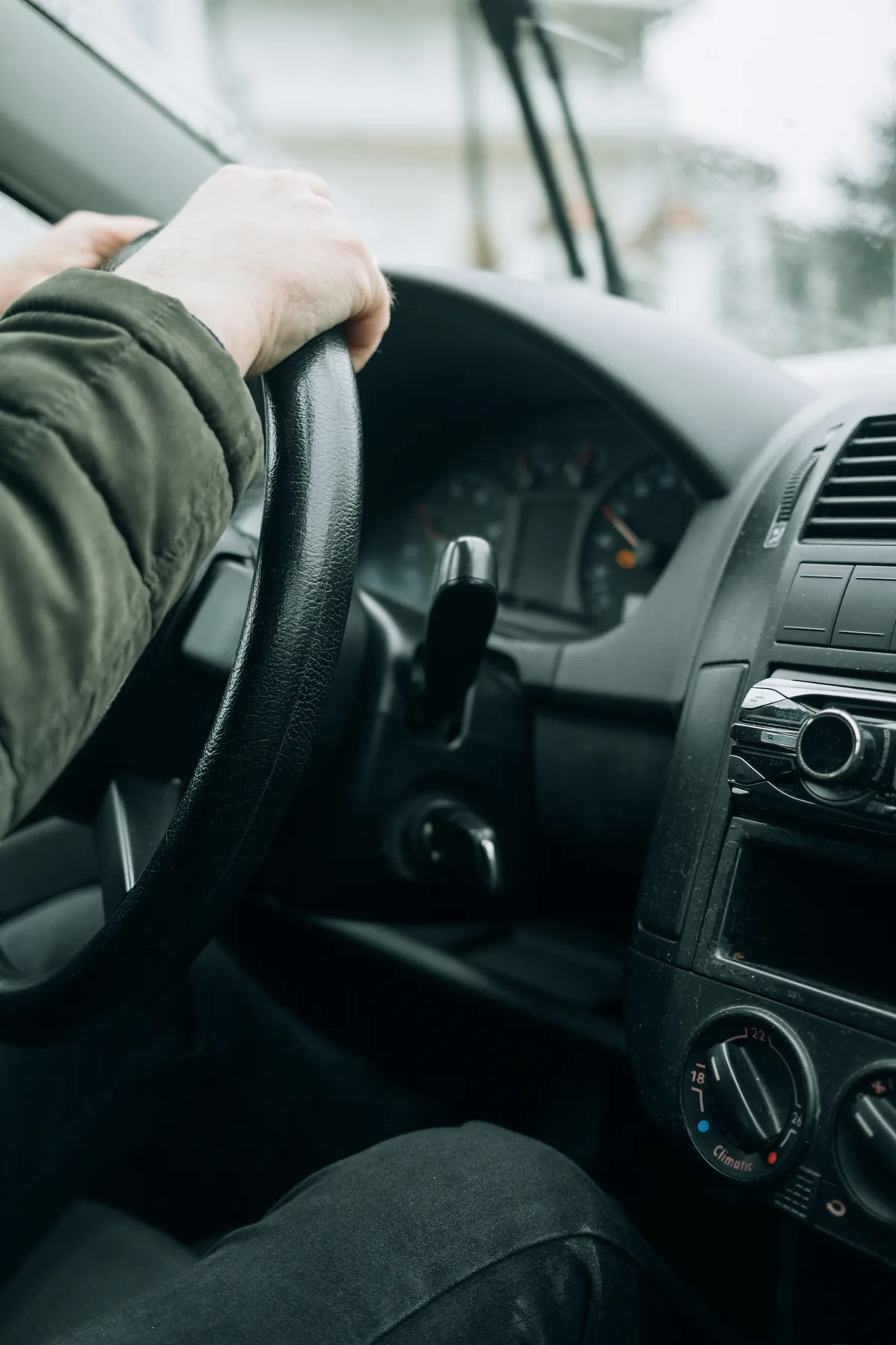Jonge bestuurder gefocust op het stuur terwijl hij door besneeuwde straten rijdt — symbool voor rijervaring en autoverzekering opbouwen