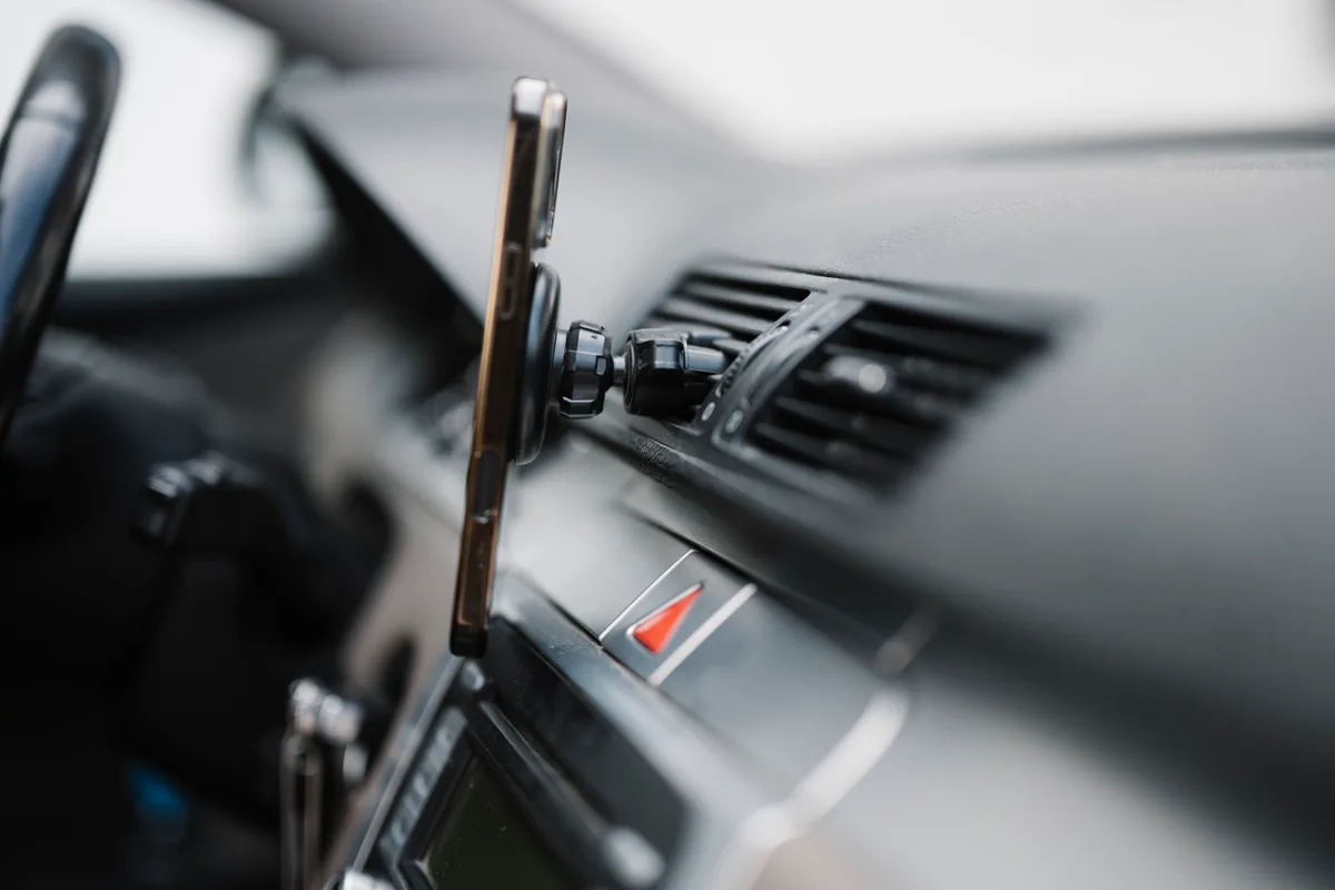 Smartphone gemonteerd op het dashboard van een rijdende auto — symbool voor in-app autoverzekering-simulatie via de verzekeraar-app