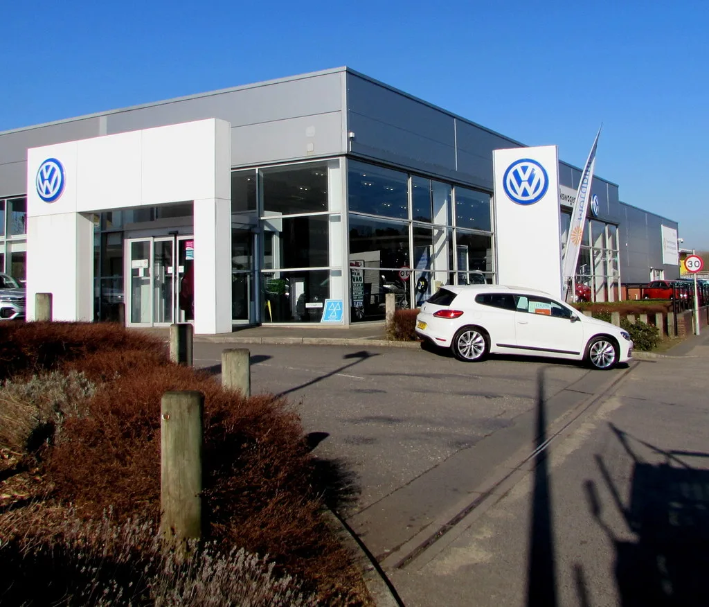 Volkswagen autodealer showroom exterieur met witte auto — garagepolis verzekering autobedrijf 2026