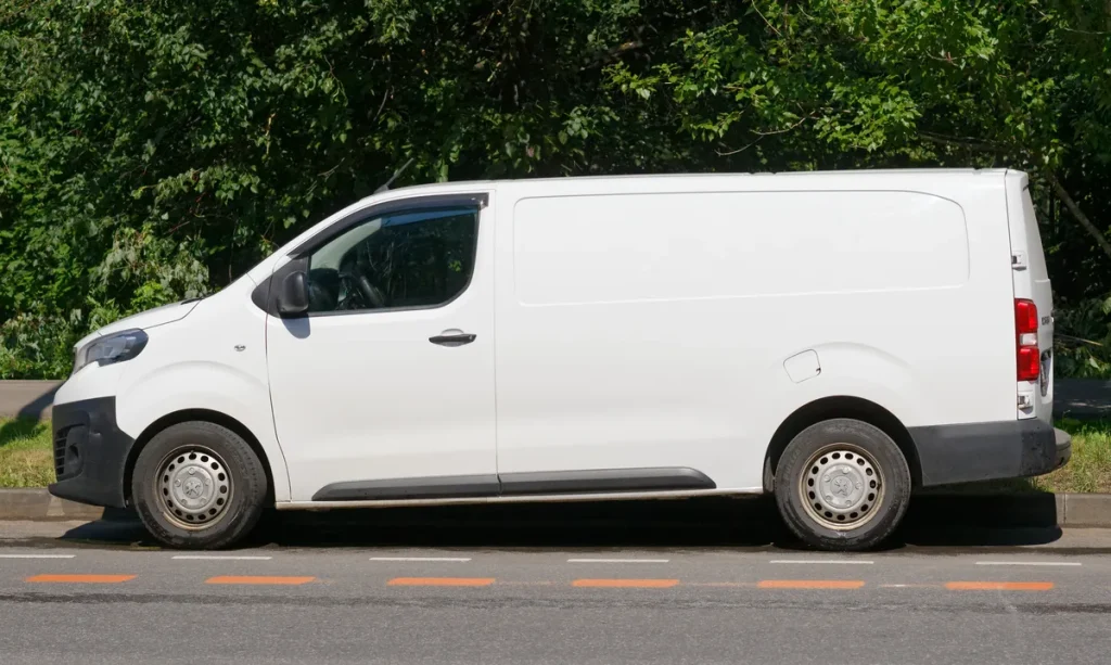 Witte bedrijfsauto bestelauto geparkeerd langs de weg — bedrijfsauto verzekering berekenen 2026