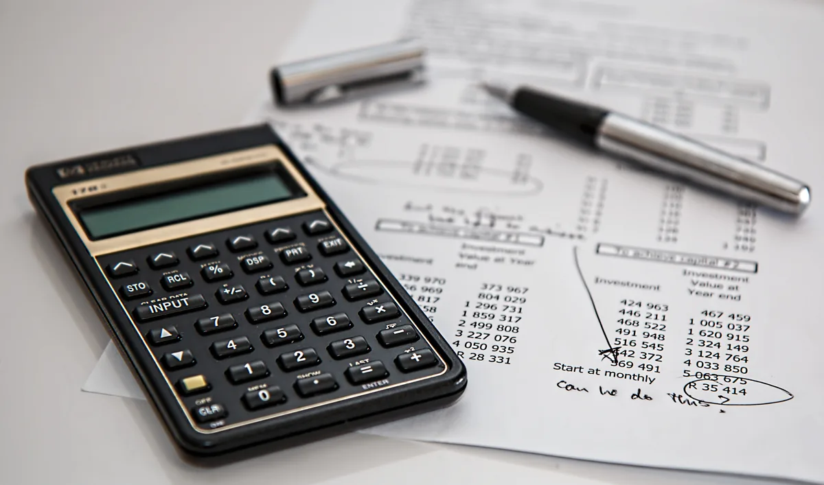 Calculator met financiële documenten en pen — bedrijfsinventaris waardebepaling voor verzekering