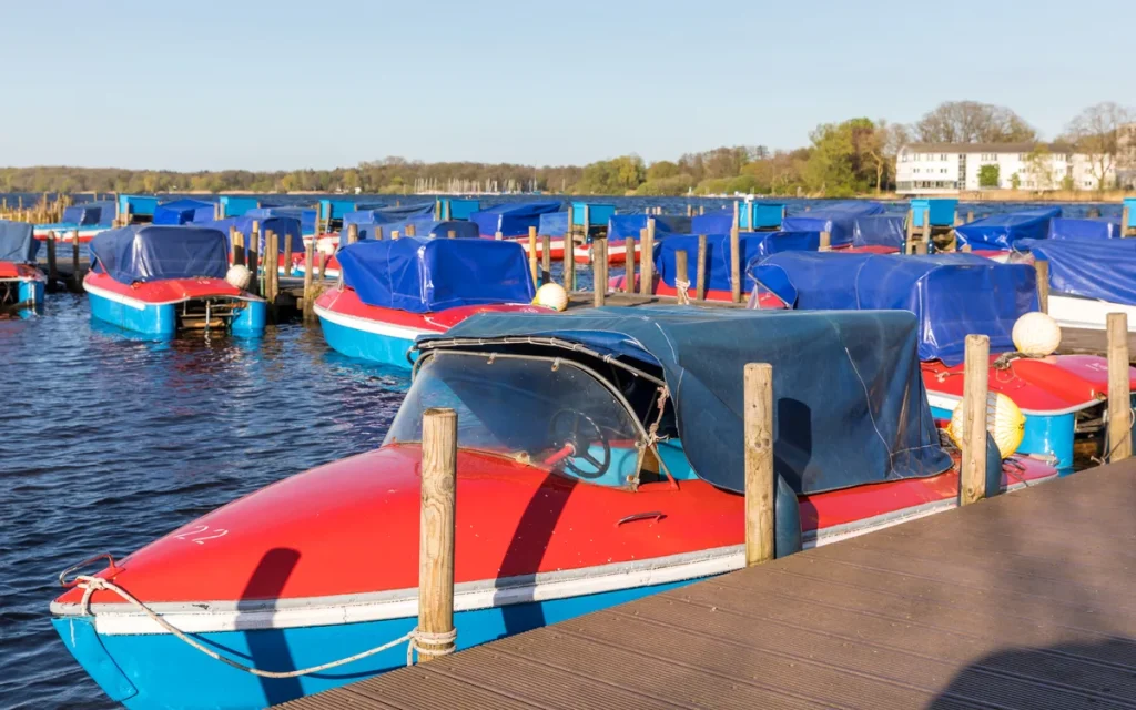 Elektrische verhuurbootjes gemeerd aan een steiger op een meer in Nederland, klaar voor verhuur aan toeristen