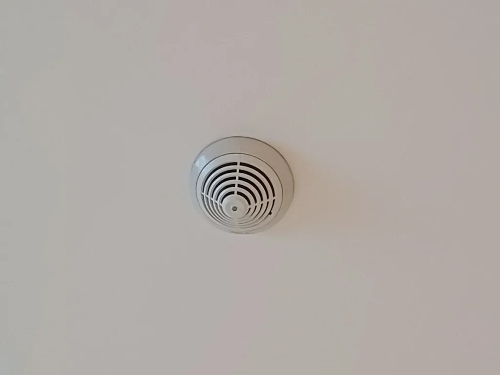 Rookmelder gemonteerd op het plafond van een kamer — brandpreventie en premiekorting opstalverzekering