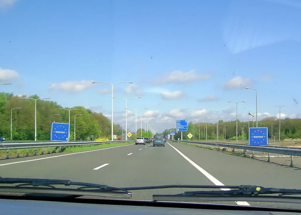 Auto rijdt de Nederlandse grens over op de snelweg bij Elten, buitenland autoverzekering