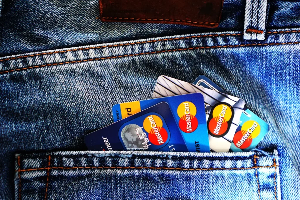 Vier Mastercard creditcards uitgewaaierd in de achterzak van een spijkerbroek