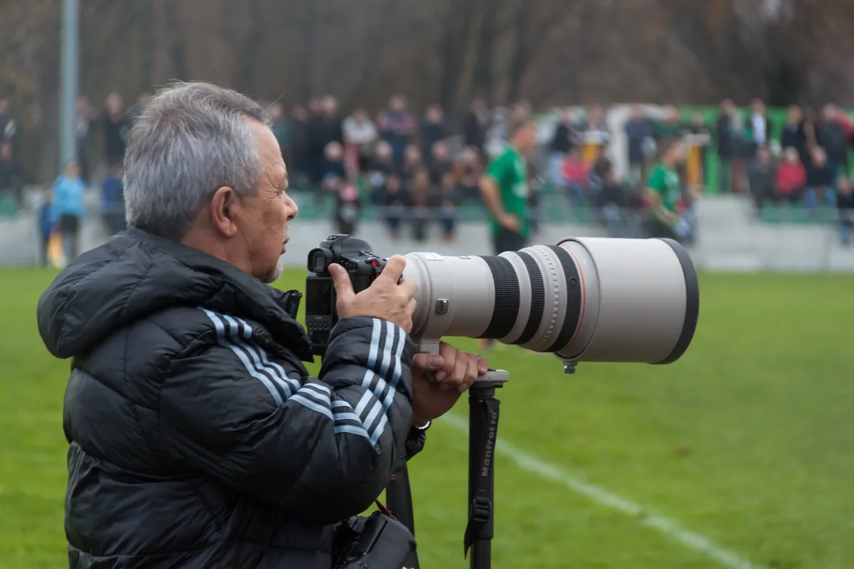 Zakelijk fotograaf met professionele Canon telephoto lens op statief tijdens opdrachtfotografie