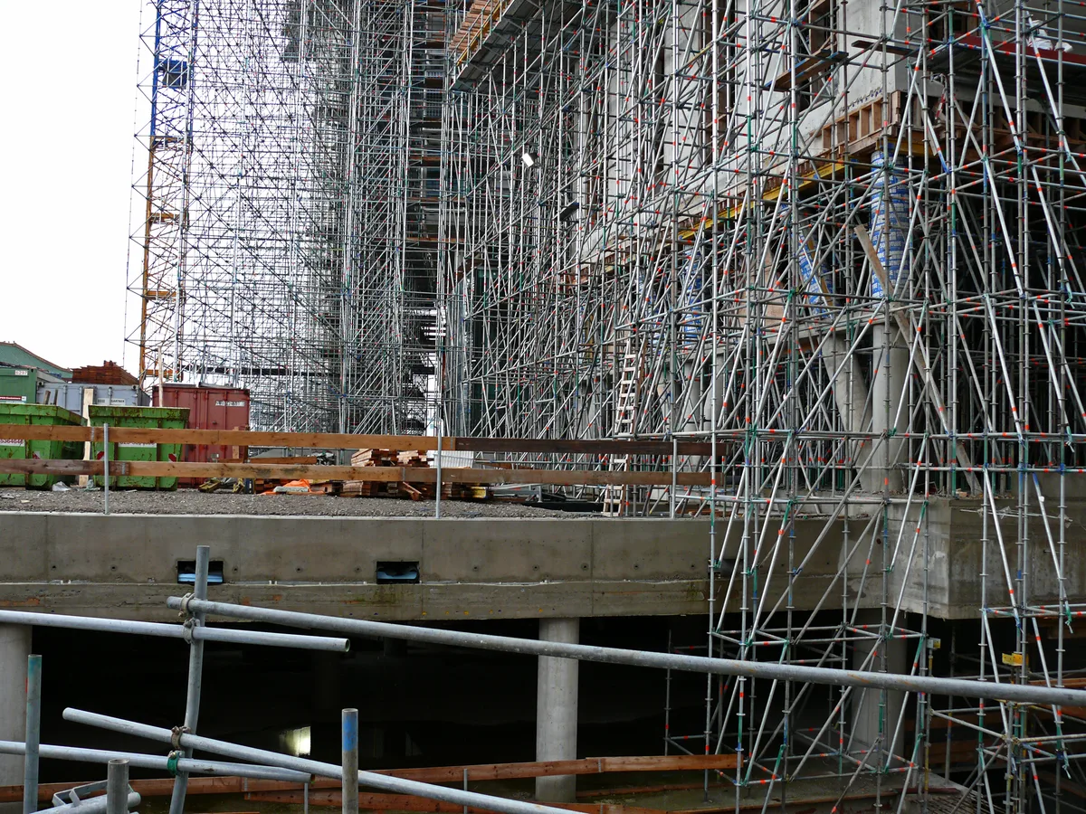 Bouwplaats Amsterdam met stellingen en betonconstructie — CAR-verzekering dekt schade aan werk in aanbouw