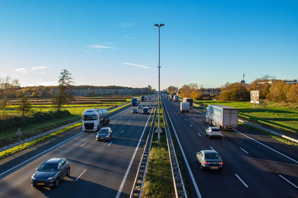 Snelweg A58 bij Tilburg met personenauto's en vrachtwagens — autoverzekering Nederland 2026