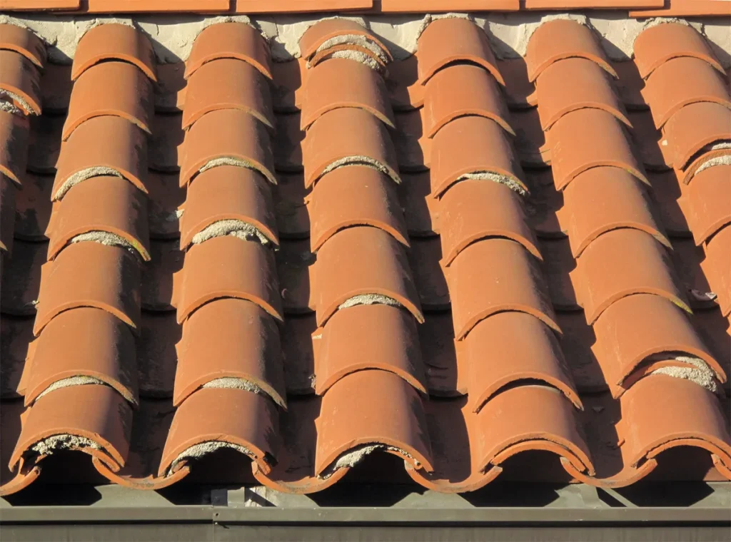 Gerepareerde rode dakpannen met cementvulling - dakschade zichtbaar na lekkage reparatie