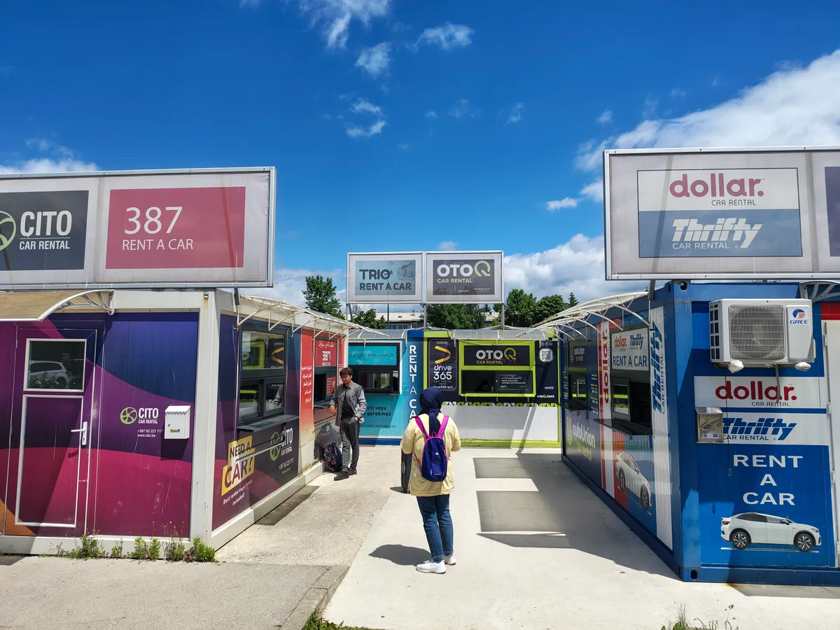Huurauto balie kiosks op luchthaven Sarajevo met verhuurders Dollar en Thrifty - EasyTerra vergelijker
