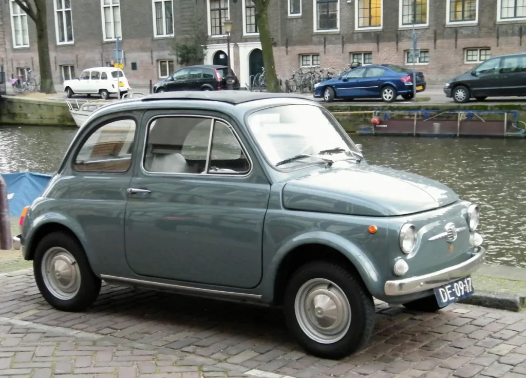 Fiat 500 geparkeerd langs een Amsterdamse gracht — compact stadsauto ideaal voor stadsverzekering