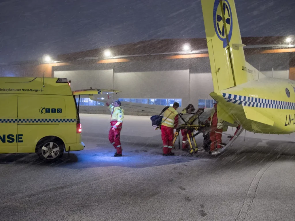 Medisch personeel laadt patient op brancard in ambulancevliegtuig voor medische repatriering