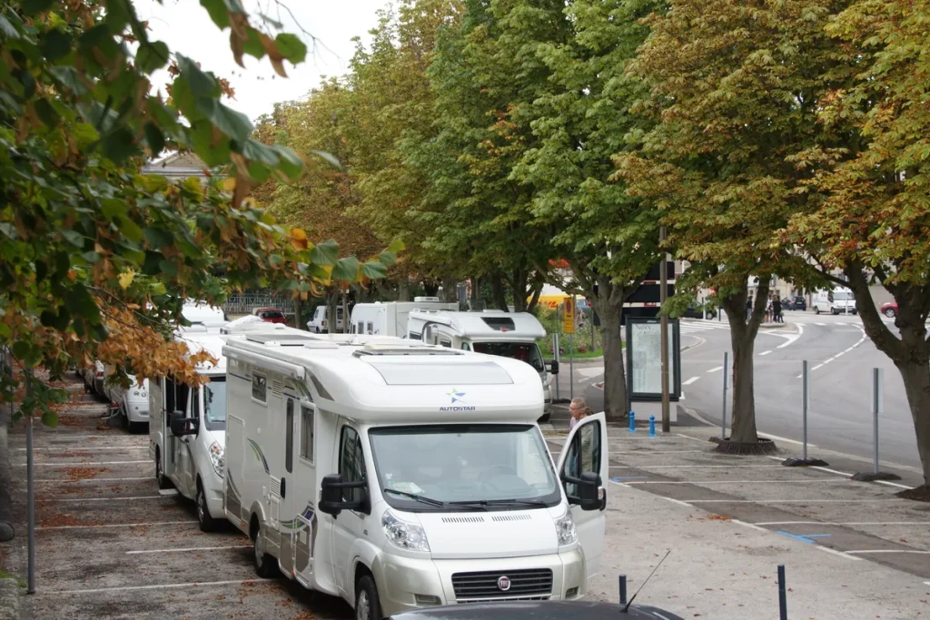 Rij witte campervans geparkeerd langs een laan — camperverzekering vergelijken 2026