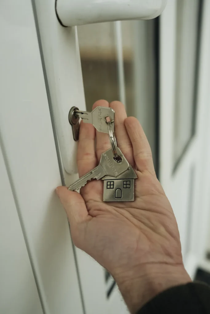 Hand houdt huissleutels bij een deurslot — symbool voor hypotheekbescherming en eigenwoningbezit