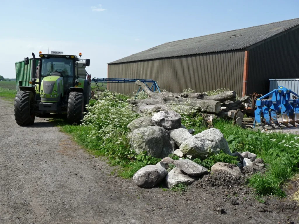 Moderne groene tractor geparkeerd naast een boerenschuur in Nederland - tractorverzekering landbouw