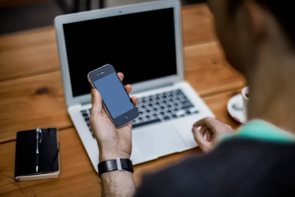 Persoon bekijkt Mijn Interpolis polis op smartphone met laptop op tafel