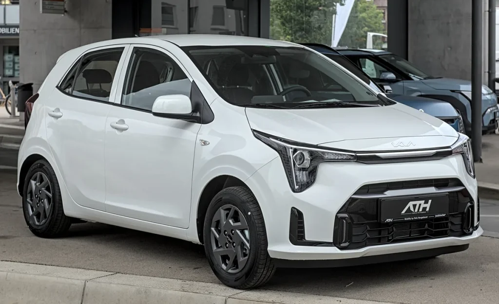 Witte Kia Picanto 2024 op een autoshow, compacte stadsauto voor verzekering vergelijking