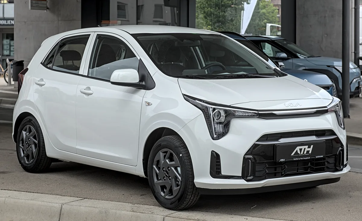 Witte Kia Picanto 2024 op een autoshow, compacte stadsauto voor verzekering vergelijking
