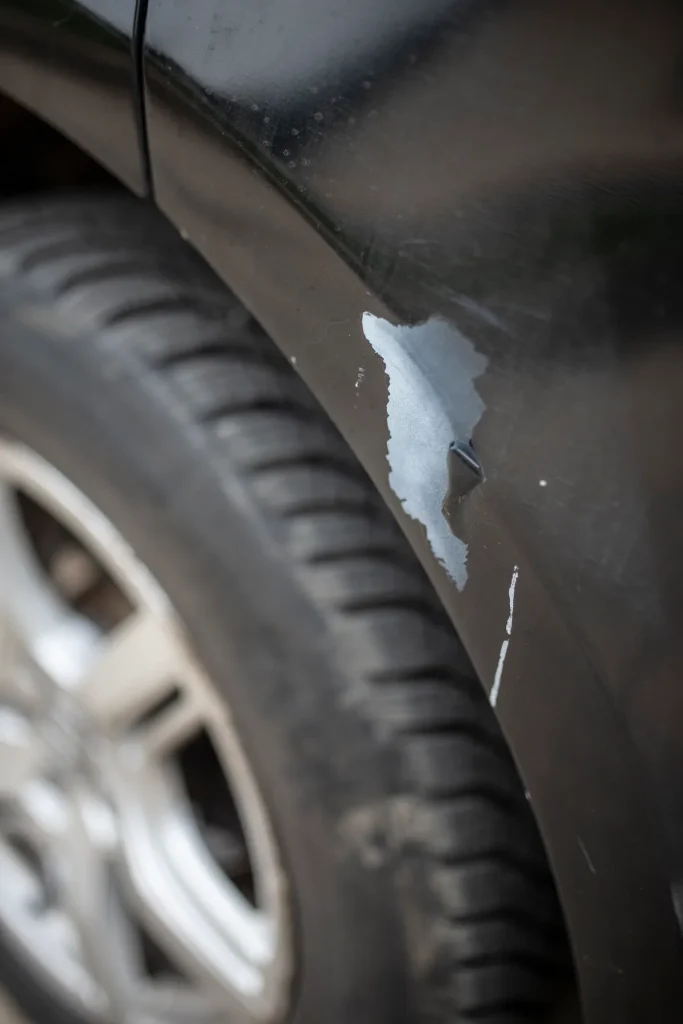 Krasschade op de lak van een auto bij een parkeerplaats, zichtbare krassen en lak beschadigd