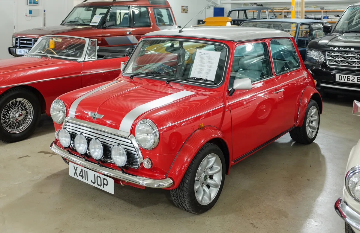 Rode Rover Mini Cooper 2000 in showroom, klassiek model met witte rallystrepen en auxlairy verlichting