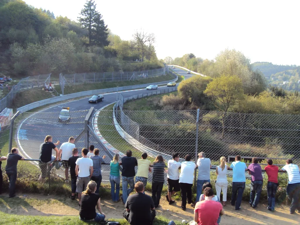 Auto's rijden door de Wehrseifen-bocht op de Nürburgring Nordschleife tijdens Touristenfahrten, toeschouwers langs de baan