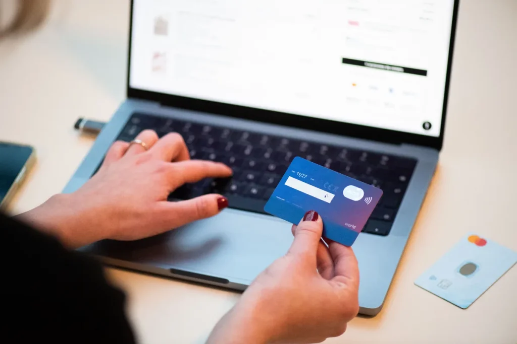 Persoon houdt Mastercard creditcard vast bij laptop voor online aankoop met webshop-koopbescherming