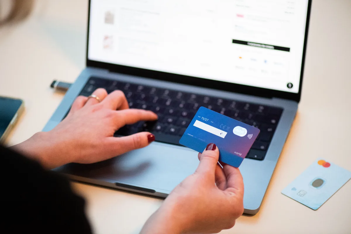 Persoon houdt Mastercard creditcard vast bij laptop voor online aankoop met webshop-koopbescherming