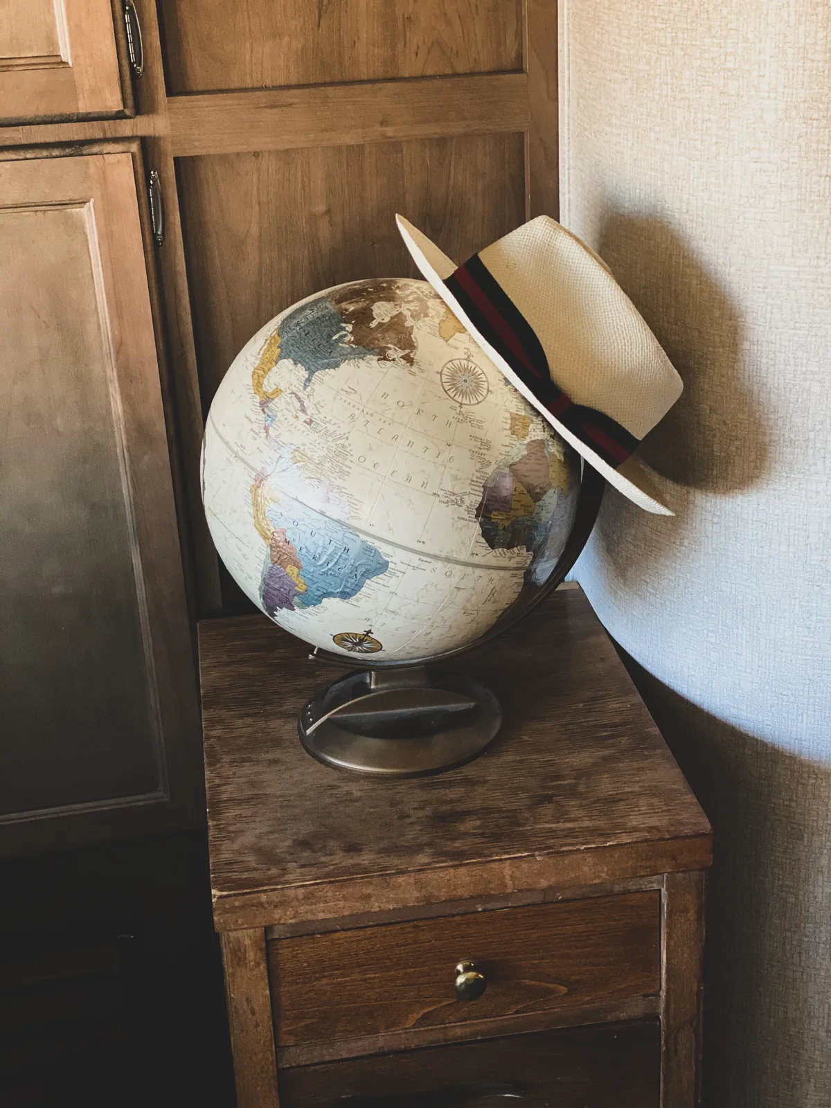 Wereldbol met reisstroohoed, symbool voor internationaal reizen en expat-verzekeringen