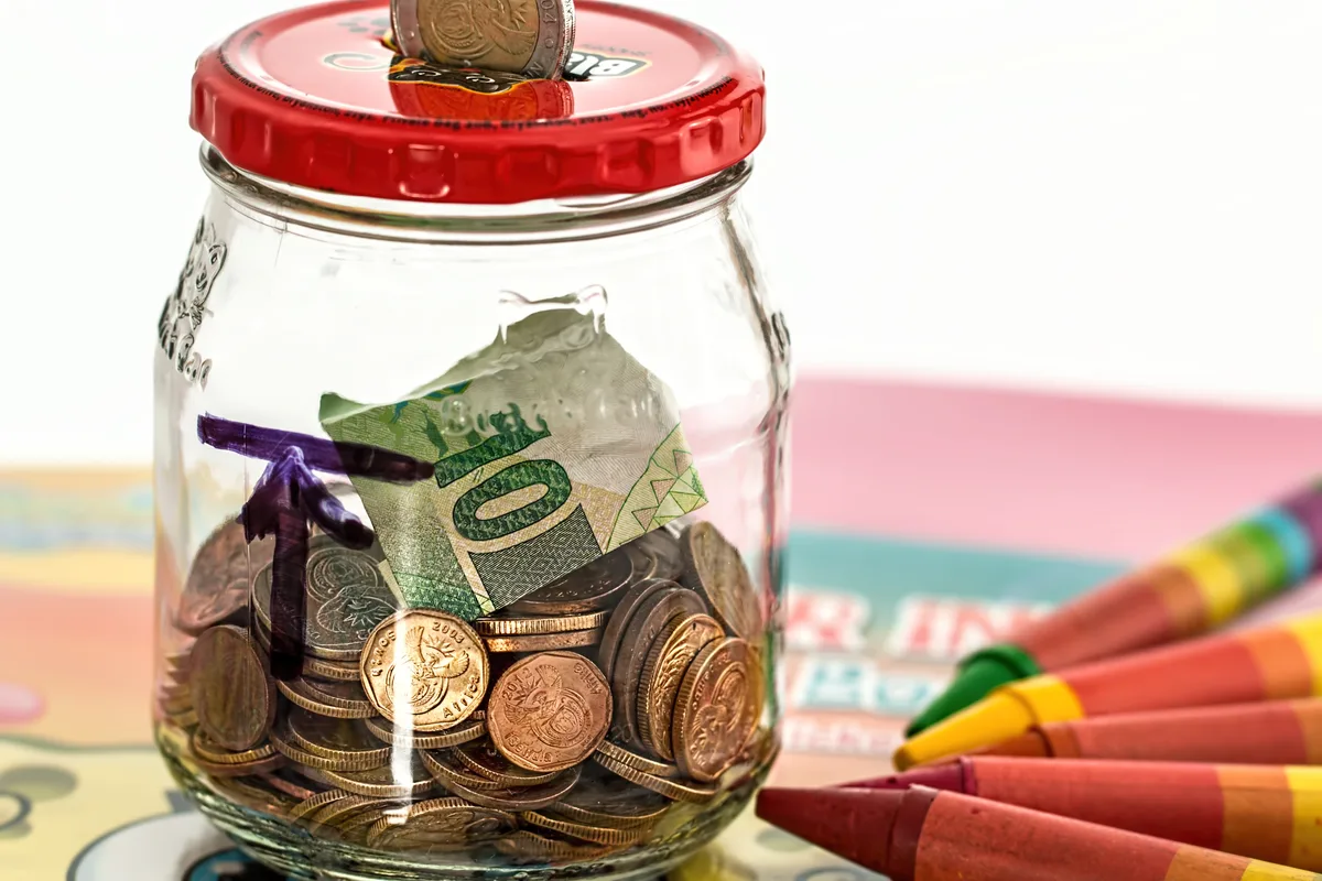 Glazen spaarpot gevuld met munten en een bankbiljet — symbool voor financiële bescherming via een overlijdensrisicoverzekering