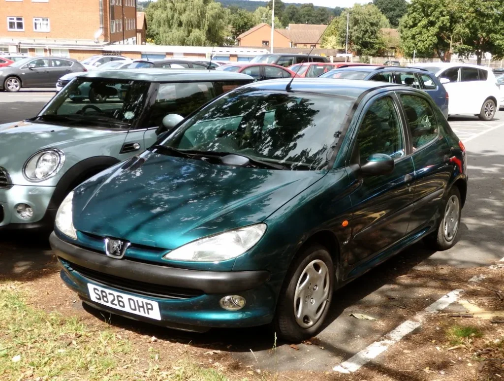 Groene Peugeot 206 uit 1998 geparkeerd op een parkeerterrein, oud occasion model