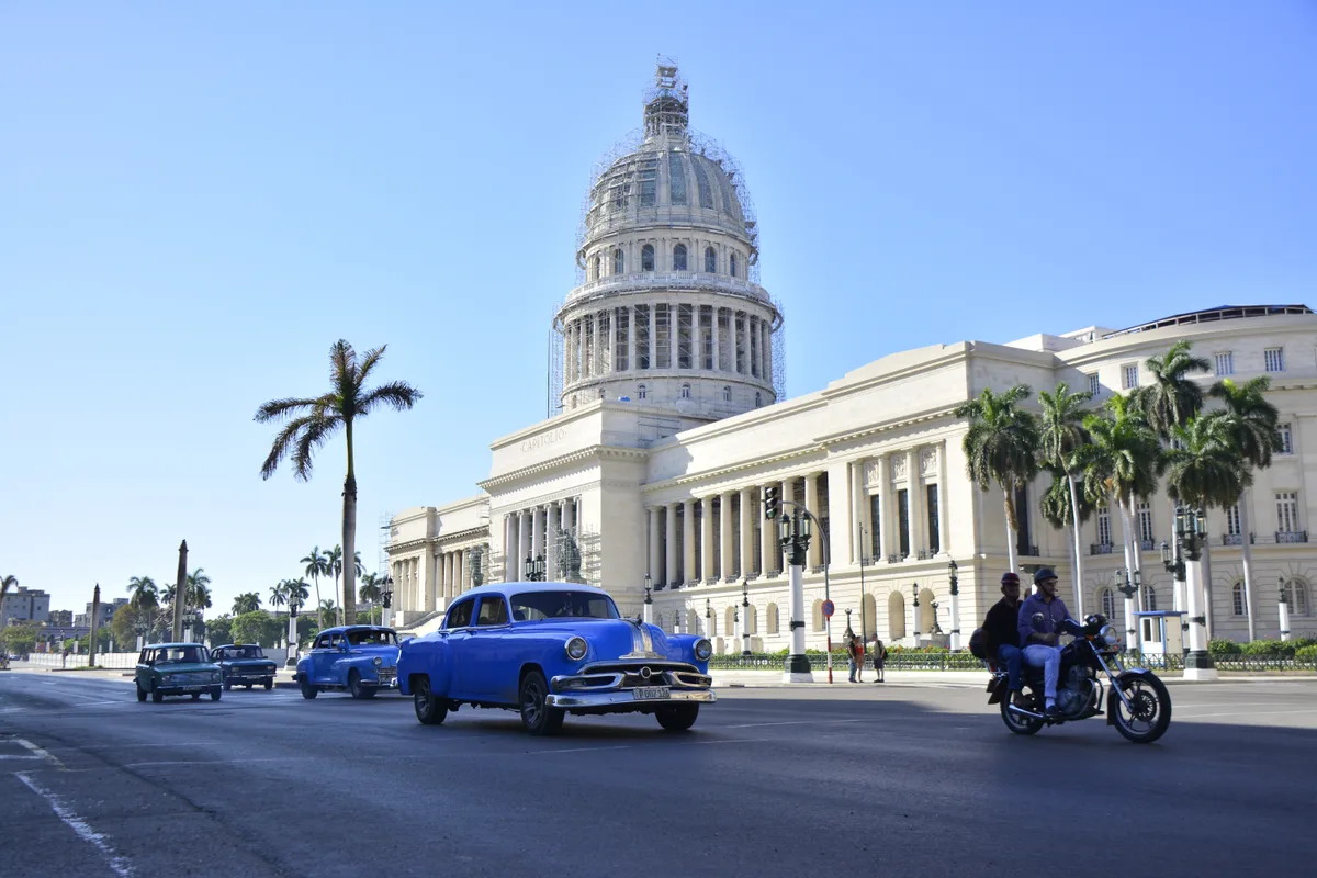 El Capitolio in Havana Cuba met klassieke vintage auto en palmbomen - reisverzekering Cuba