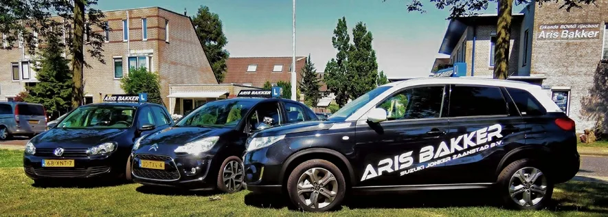 Bedrijfspand en wagenpark van autorijschool Aris Bakker met lesautos geparkeerd voor de deur