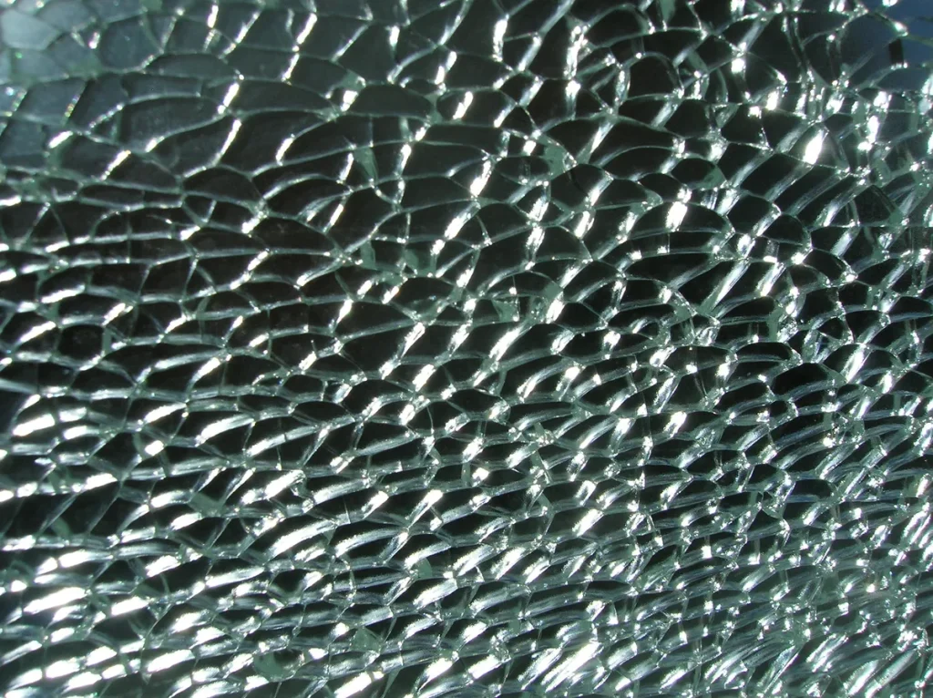 Gebarsten autoglas van dichtbij: getempereerd veiligheidsglas van een autoruit volledig versplinterd