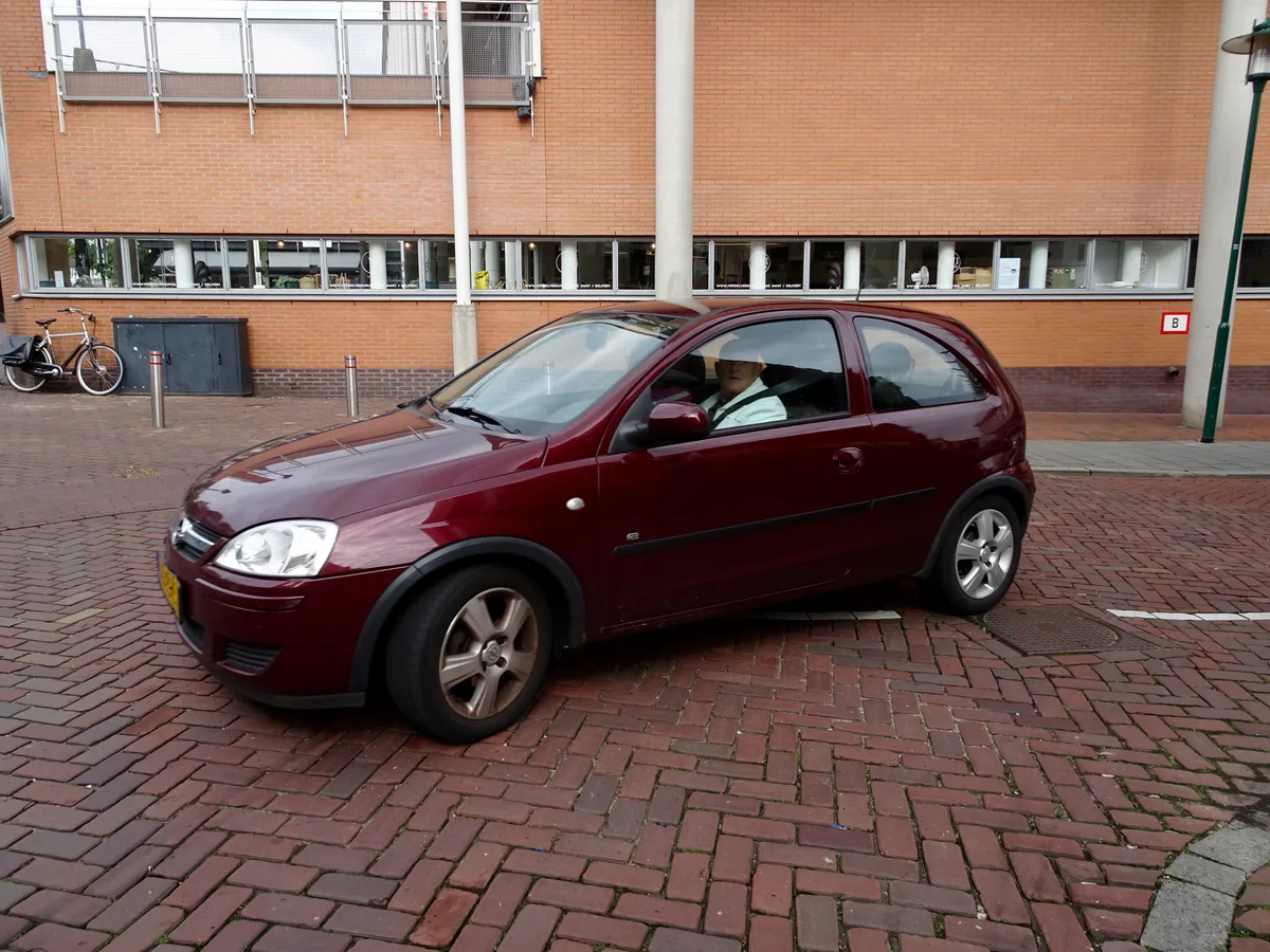 Man rijdt in een rode auto door een Nederlandse stad — schadevrije jaren en autoverzekering