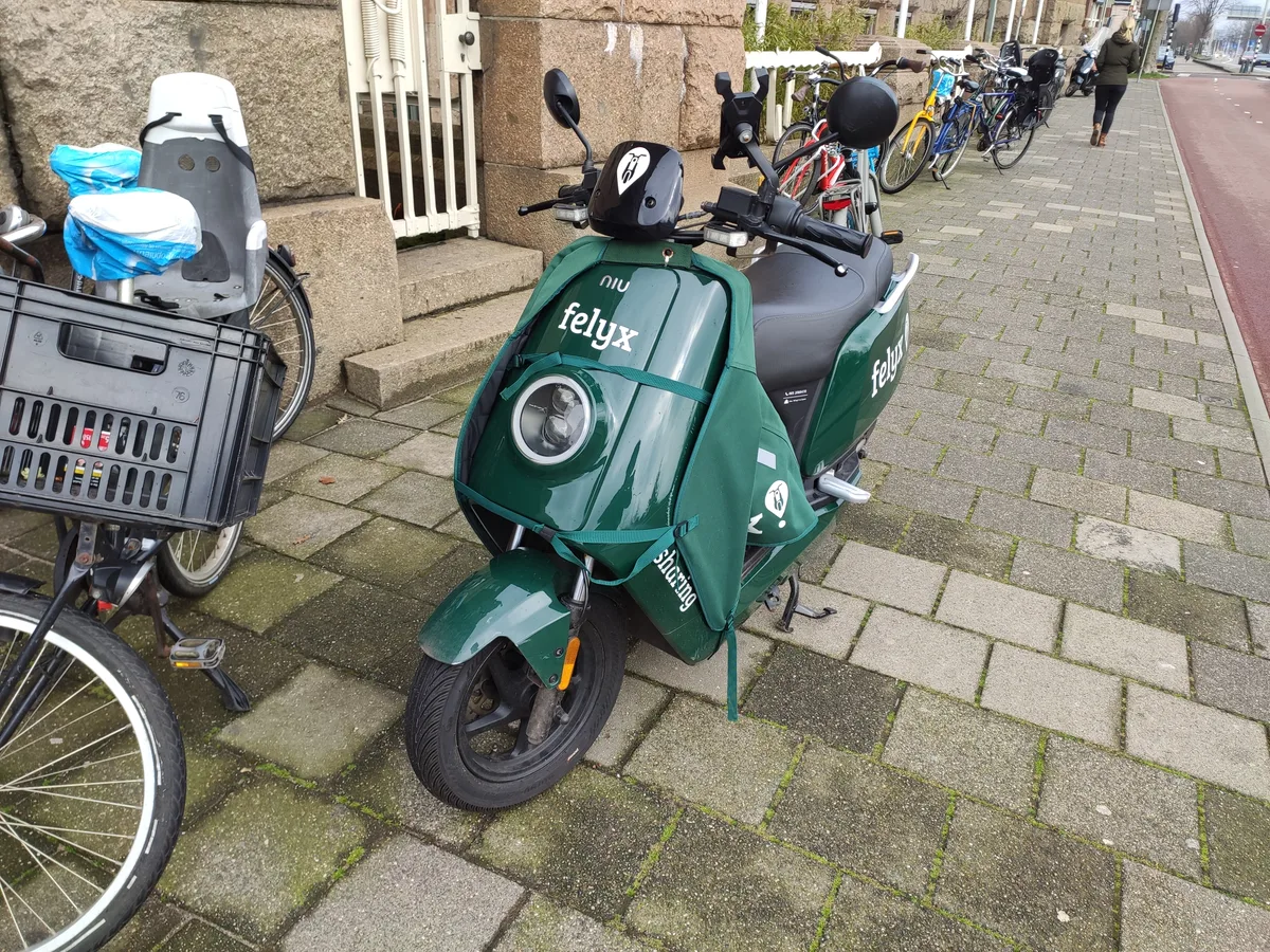 Groene Felyx elektrische scooter geparkeerd op stoep in Den Haag, Nederland 2020