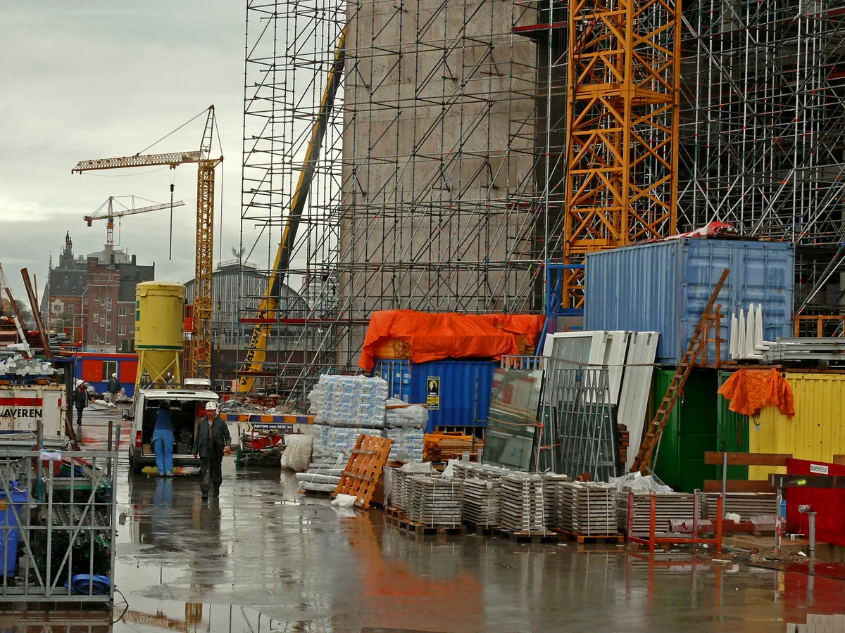 Bouwplaats met grote steigerconstructies en kranen in Amsterdam, passend bij steigerbouw verzekering