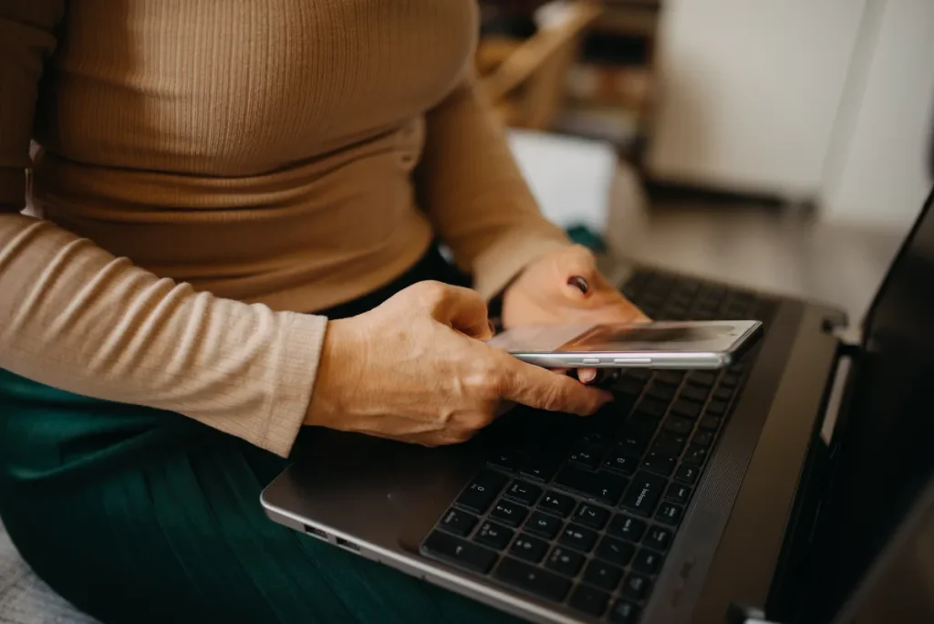 Vrouw gebruikt smartphone thuis — telefoon meeverzekerd op inboedelverzekering