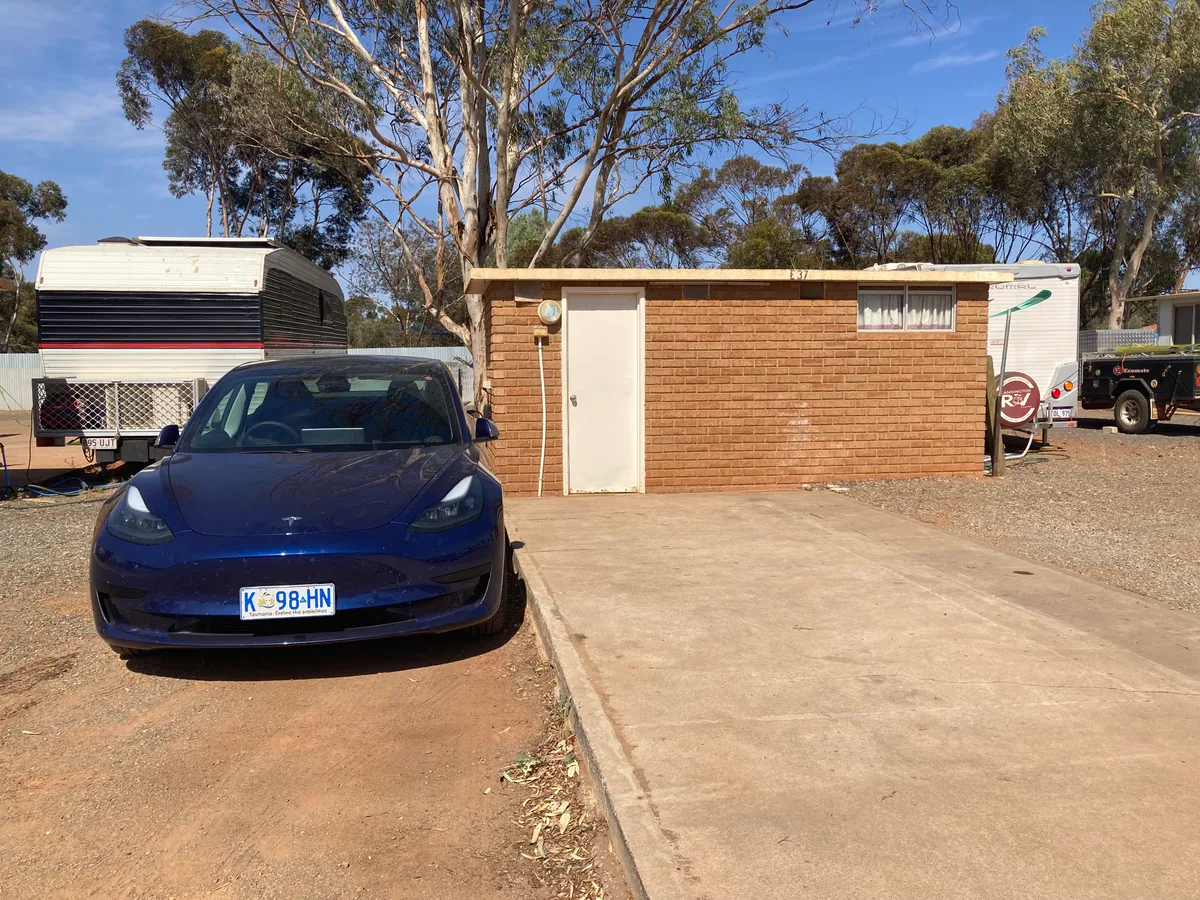 Blauwe Tesla Model 3 geparkeerd bij een laadpunt - Tesla autoverzekering vergelijken
