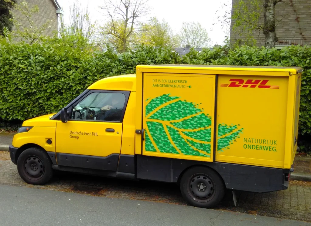 DHL elektrische bezorgbus levert pakketten af in woonwijk Nederland — transport goederenverzekering 2026